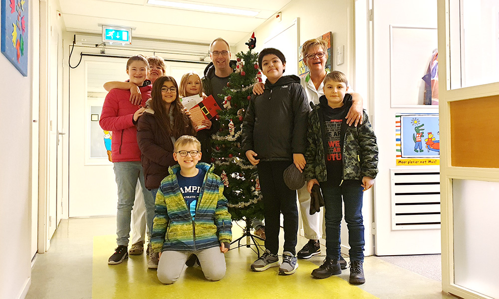 De leerlingenraad en meester Koen bij de kerstboom samen met verpleegkundigen Ilona en Willie